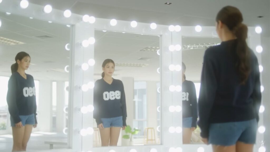 A sapphic character from Show Me Love, a Thai GL series, looks at herself in the mirror, reflecting the emotional weight behind the stories we love.