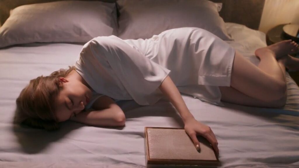 Earn from The Secret of Us lies in bed holding a small box of memories, symbolizing withheld truths and emotional burdens.
