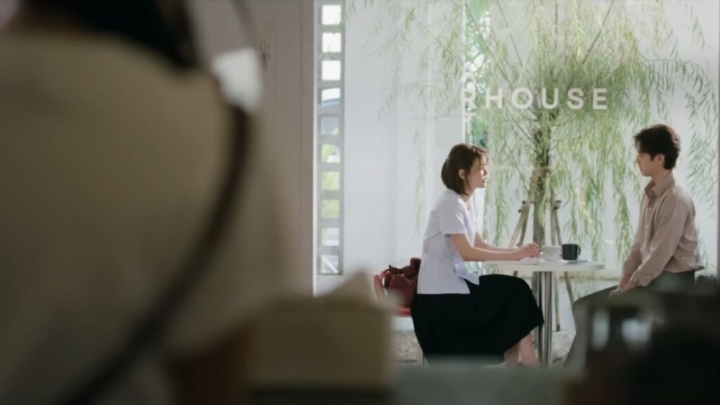 Dokrak gazing at Pam in a quiet café moment, capturing the silent yearning at the heart of US.